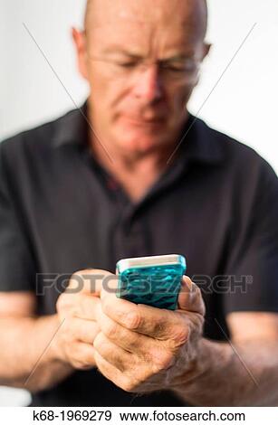 Stock Photo - Soft focus on a smart phone, used by a middle-aged man. Fotosearch