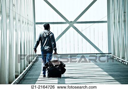 Solo traveler, one. Man back dragging his wheeled suitcase on a walkway, catwalk, gangway. Airport, El Prat de Llobregat, Barcelona, Catalonia, Spain. View Large Photo Image Stock Photograph - Solo traveler, one. Man back dragging his wheeled suitcase on a walkway, catwalk, gangway. Airport, El Prat de Llobregat, Barcelona, Catalonia, Spain.. Fotosearch