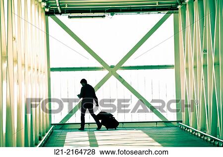 Solo traveler, one. Man dragging his wheeled suitcase while he is using his smartphone on a walkway, catwalk, gangway. Airport, El Prat de Llobregat, Barcelona, Catalonia, Spain. View Large Photo Image Stock Photo - Solo traveler, one. Man dragging his wheeled suitcase while he is using his smartphone on a walkway, catwalk, gangway. Airport, El Prat de Llobregat, Barcelona, Catalonia, Spain.. Fotosearch