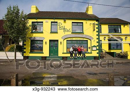 Stock Image - Some girls posing in front of a colorful Irish building in Kinvara Harbour, Co. Galway, Ireland. Fotosearch