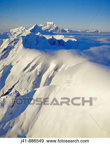 Stock Photo - Southeasterly cloud spilling over the Main divide of the Southern Alps Aoraki / Mt Cook in the distance Westland National Park New Zealand. Fotosearch