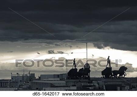 Stock Photo - Spain, Madrid, elevated view of figures atop BBVA building, from the Circulo de Bellas Artes, sunset. Fotosearch