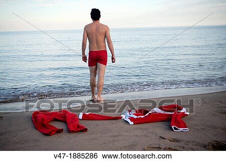 Spain, Rear view of man walking into sea, Santa Claus costume on beach View Large Photo Image Stock Photograph - Spain, Rear view of man walking into sea, Santa Claus costume on beach. Fotosearch
