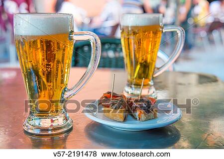 Stock Photo - Spanish aperitif: two glasses of beer with tapa on a terrace. Madrid, Spain.. Fotosearch