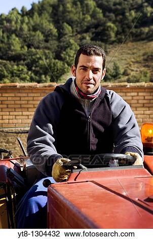 Stock Image - Spanish male farm worker at the steering wheel of a tractor. Fotosearch