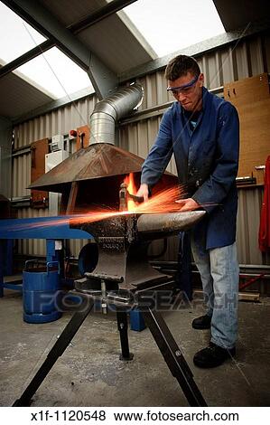 Sparks flying off hot metal as a young man learns basic blacksmith skills at Ceredigion Training vocational education centre Aberystwyth Wales UK View Large Photo Image Stock Photo - Sparks flying off hot metal as a young man learns basic blacksmith skills at Ceredigion Training vocational education centre Aberystwyth Wales UK. Fotosearch