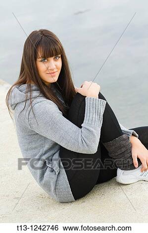 Sporting young woman is sitting on a concrete pier View Large Photo Image Stock Photograph - Sporting young woman is sitting on a concrete pier. Fotosearch
