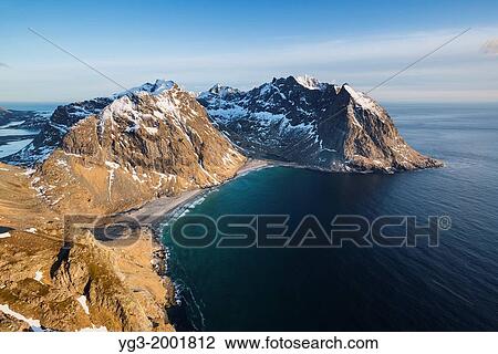 Stock Image - Spring snow and Kvalvika beach seen from Ryten mountain summit, Moskenesoy, Lofoten Islands, Norway.. Fotosearch