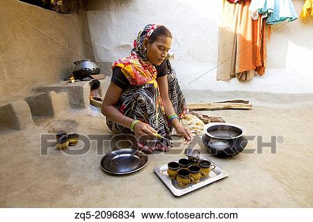 Squatting woman pouring tea in kitchen, Gond tribe, Gadchiroli, Maharashtra, India. View Large Photo Image Picture - Squatting woman pouring tea in kitchen, Gond tribe, Gadchiroli, Maharashtra, India.. Fotosearch