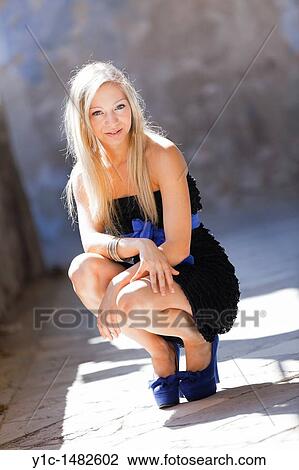Stock Image - Squatting young fanciful woman in Blue high heels. Fotosearch