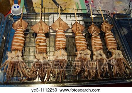 Squid on a stick for sale in a night market in Northern Thailand View Large Photo Image Stock Image - Squid on a stick for sale in a night market in Northern Thailand. Fotosearch