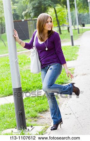 Stock Image - Standing by the column young woman. Fotosearch
