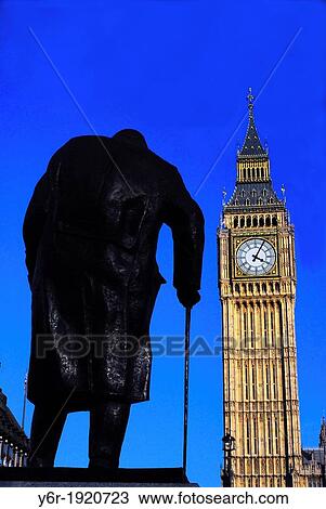 Stock Image - Statue of Winston Churchill, portrayed as a very old but bullish man, looking at Big Ben in Westminster, London, England, on a Winter day of intense sunshine. Fotosearch
