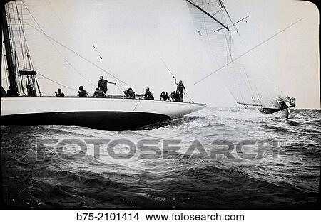Picture - Stern of a classic sailboat in a regatta with sailors in the background at the Port Mahon, Menorca, Balearic Islands, Spain.. Fotosearch