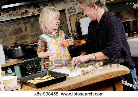 Stock Photo - Stock photo of a four year old girl and her mother baking cookies together in the kitchen. Fotosearch