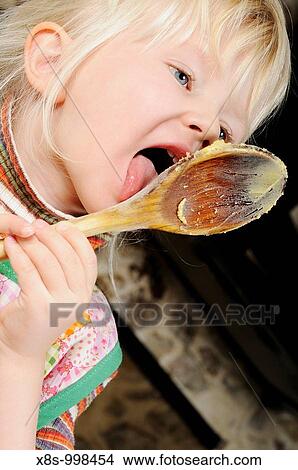 Stock photo of a little girl licking the cookie mixture of a wooden spoon as she helps her mum bake some biscuits View Large Photo Image Picture - Stock photo of a little girl licking the cookie mixture of a wooden spoon as she helps her mum bake some biscuits. Fotosearch