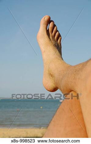 Stock photo of a mans foot as he is lying on the beach recharging his batteries on his summer holidays View Large Photo Image Stock Image - Stock photo of a mans foot as he is lying on the beach recharging his batteries on his summer holidays. Fotosearch