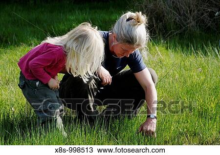 Stock photo of a mother and her 3 year old daughter looking at insects hidden in the grass View Large Photo Image Stock Image - Stock photo of a mother and her 3 year old daughter looking at insects hidden in the grass. Fotosearch