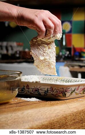 Stock Photo - Stock photo of a turkey escalope being dipped into flour. Fotosearch