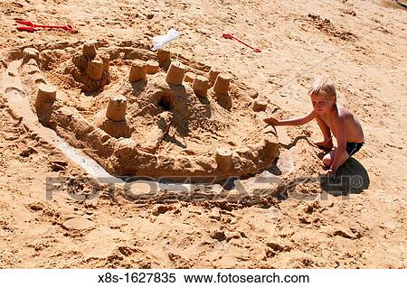 Stock photo of a young boy making a sandcastle on the beach View Large Photo Image Stock Photography - Stock photo of a young boy making a sandcastle on the beach. Fotosearch
