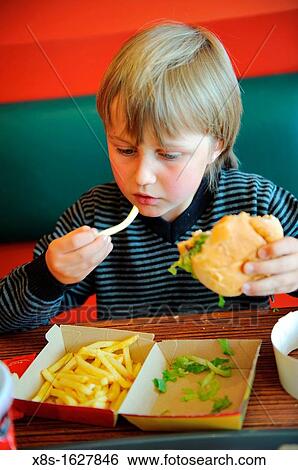 Stock Photograph - Stock photo of an 11 year old boy eating fast food in a restaurant. Fotosearch
