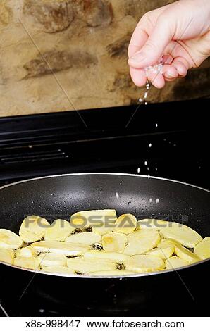 Stock photo of salt being added to potatoes frying in a pan View Large Photo Image Stock Photo - Stock photo of salt being added to potatoes frying in a pan. Fotosearch