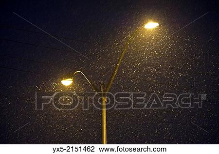 Street lamps illuminate falling snow on a deserted street at night in Toronto suburbs. View Large Photo Image Stock Image - Street lamps illuminate falling snow on a deserted street at night in Toronto suburbs.. Fotosearch