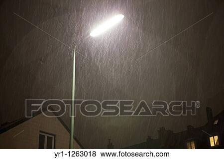 Stock Photo - Street light during snowfall at night. Residental houses in the backgroun, Munich, Germany.. Fotosearch