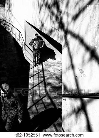 Stock Image - Street musician playing the accordion at the exit of the train station.. Fotosearch