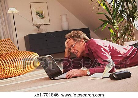 Stressed middleaged man is lying on the floor with a notebook View Large Photo Image Stock Photograph - Stressed middleaged man is lying on the floor with a notebook. Fotosearch