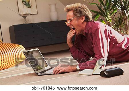 Stressed middleaged man is lying on the floor with a notebook View Large Photo Image Stock Photography - Stressed middleaged man is lying on the floor with a notebook. Fotosearch