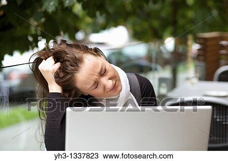 Stock Image - Stressed young woman with a laptop outdoor. Fotosearch