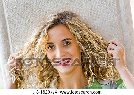 Picture - Stretching her curly hair young woman. Fotosearch