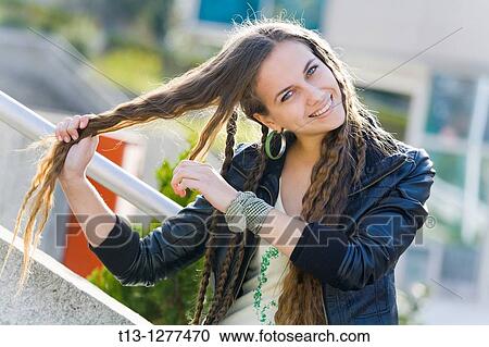 Stock Image - Stretching her long hair smiling young woman. Fotosearch