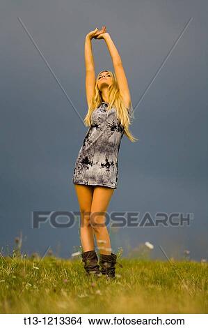 Picture - Stretching in the open young woman in a very short dress and boots. Fotosearch