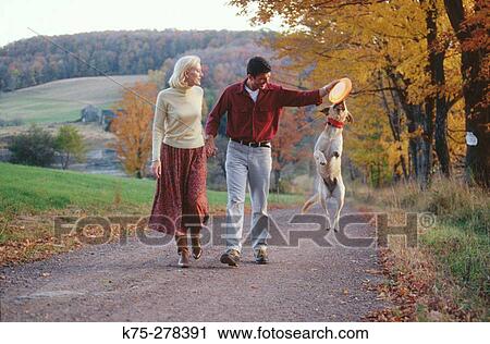 Stock Image - Strolling down a country road with dog. Fotosearch