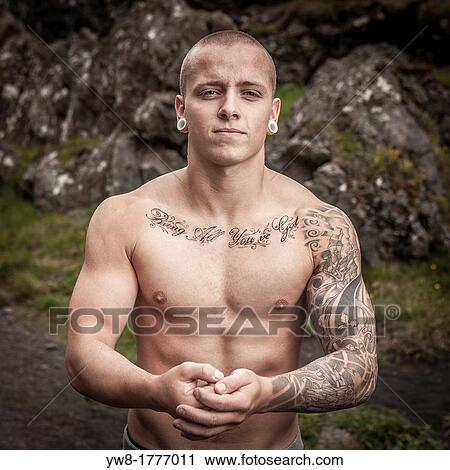 Stock Image - Strong man with Tattoos and gaged ears, Djupalonssandur, Snaefellsnes Peninsula, Iceland. Fotosearch