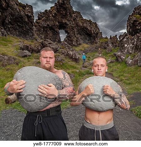 Stock Photo - Strong men brothers holding heavy stones, Djupalonssandur, Snaefellsnes Peninsula, Iceland. Fotosearch