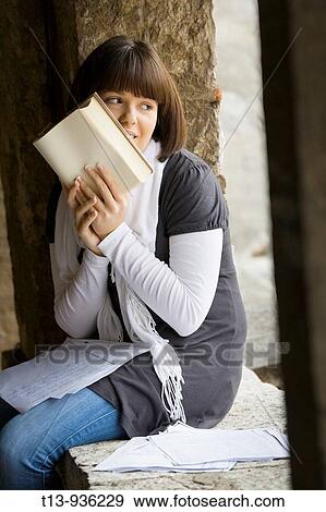Stock Photo - Student young woman is hiding her face behind a book. Fotosearch