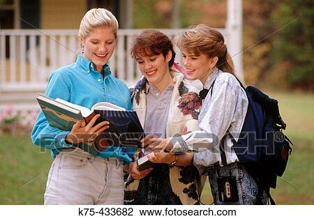 Stock Image - Students looking over books together. Fotosearch