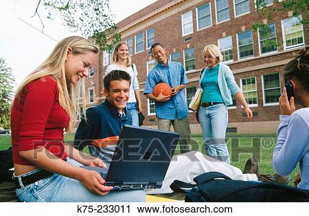 Stock Image - Students with laptop on lawn. Fotosearch