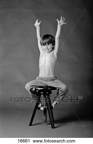 Studio portrait of boy stretching his arms up while sitting on stool View Large Photo Image Stock Image - Studio portrait of boy stretching his arms up while sitting on stool. Fotosearch
