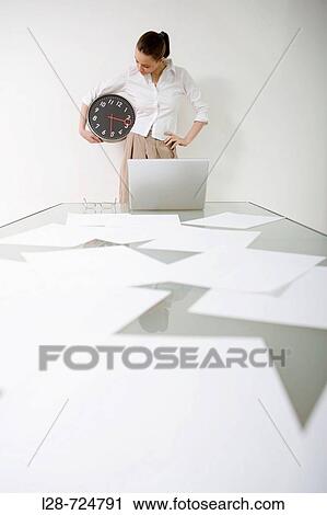 Studio portrait of young businesswoman holding clock View Large Photo Image Stock Image - Studio portrait of young businesswoman holding clock. Fotosearch