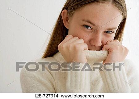 Studio portrait of young woman covering face with turtleneck collar View Large Photo Image Picture - Studio portrait of young woman covering face with turtleneck collar. Fotosearch