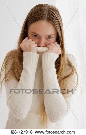 Studio portrait of young woman covering face with turtleneck collar View Large Photo Image Stock Photo - Studio portrait of young woman covering face with turtleneck collar. Fotosearch