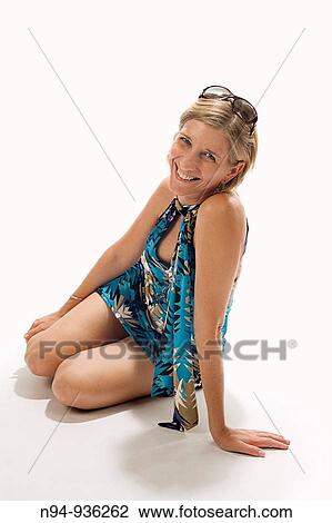 Stock Image - Studio shot of blonde girl sitting on the floor.. Fotosearch