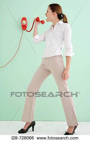 Stock Photograph - Studio shot of businesswoman yelling at telephone. Fotosearch