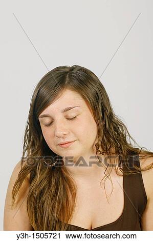 Stock Image - Studio shot of female teenager, eyes closed. Fotosearch