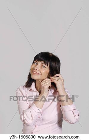 Studio shot of woman, putting earrings in View Large Photo Image Stock Image - Studio shot of woman, putting earrings in. Fotosearch