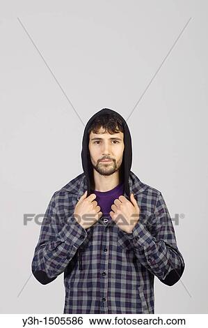 Stock Photograph - Studio shot of young man, hooded jacket. Fotosearch